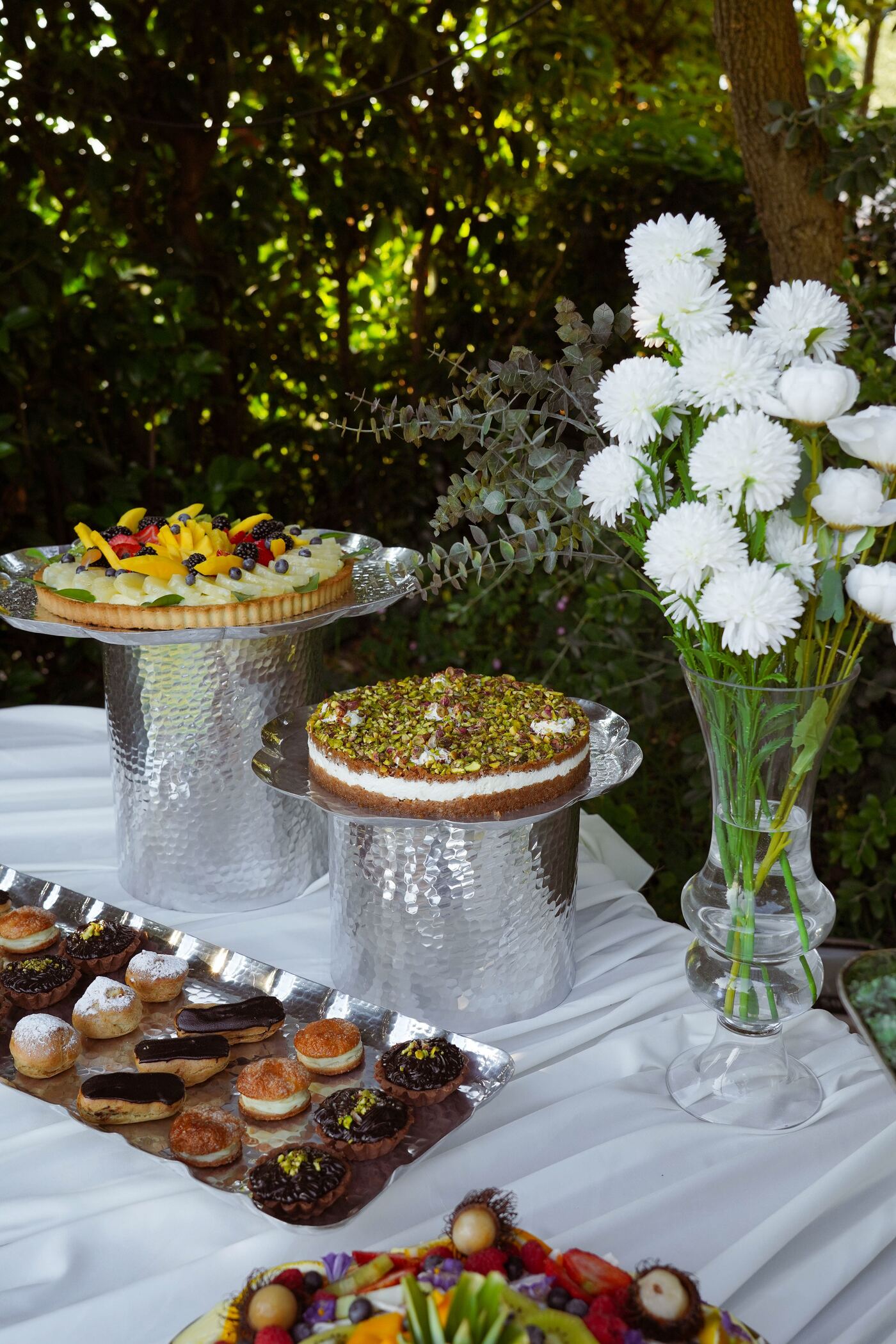 Tiered silver stands of fruit tart, pistachio cheesecake and petits fours