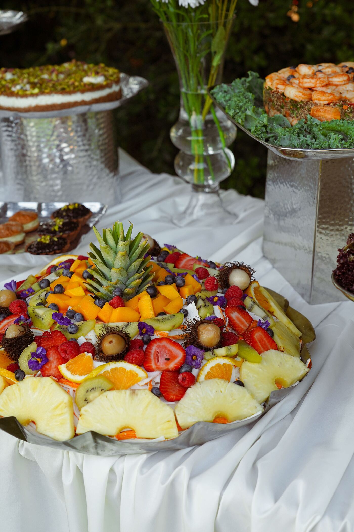 A composed platter of tropical fruit — pineapple, mango, strawberries and berries